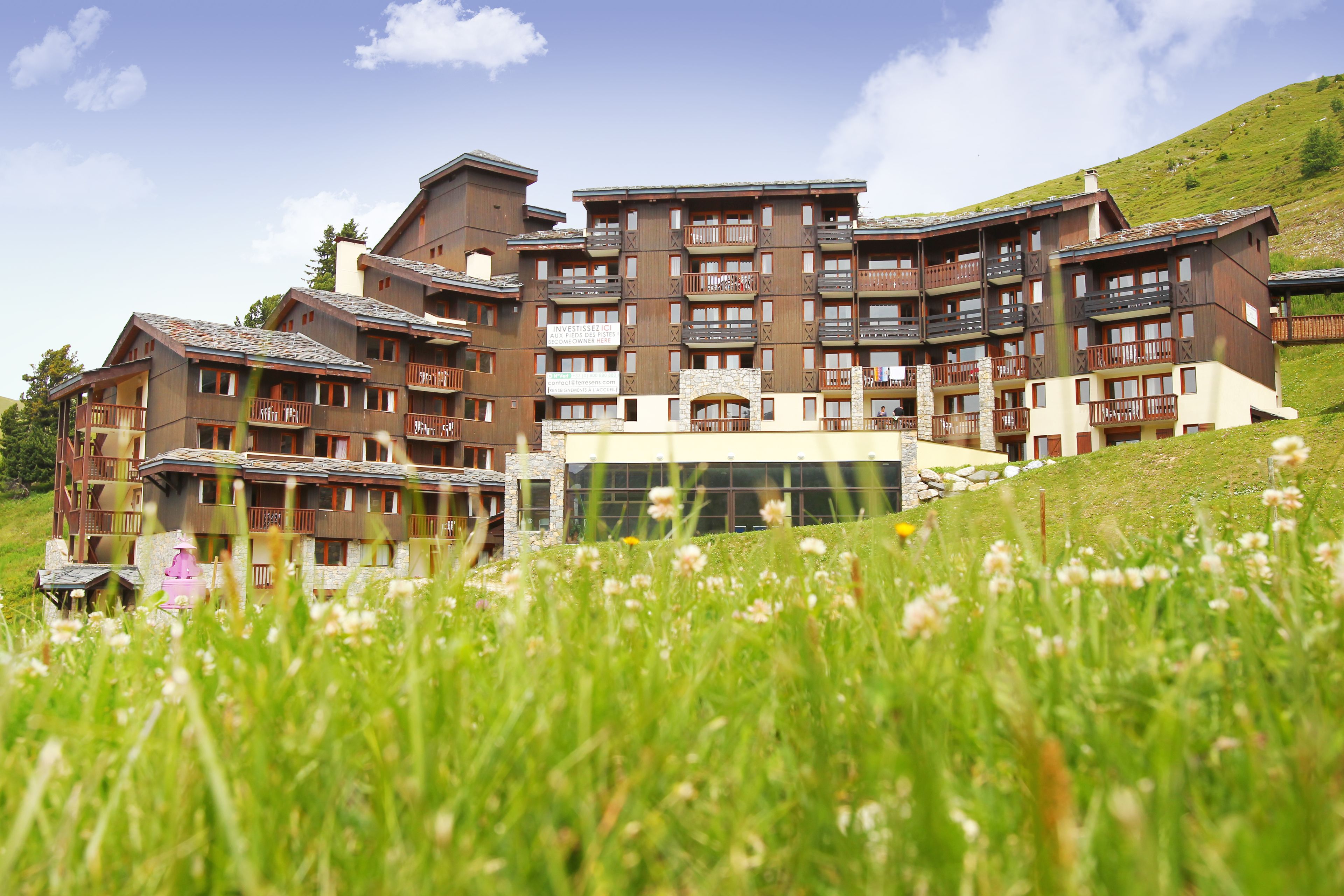 A multi-story hotel with balconies and a stone facade, surrounded by a grassy area.