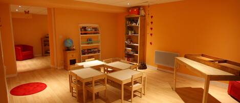 A room with a wooden floor, a red chair, a wooden table, and a bookshelf.