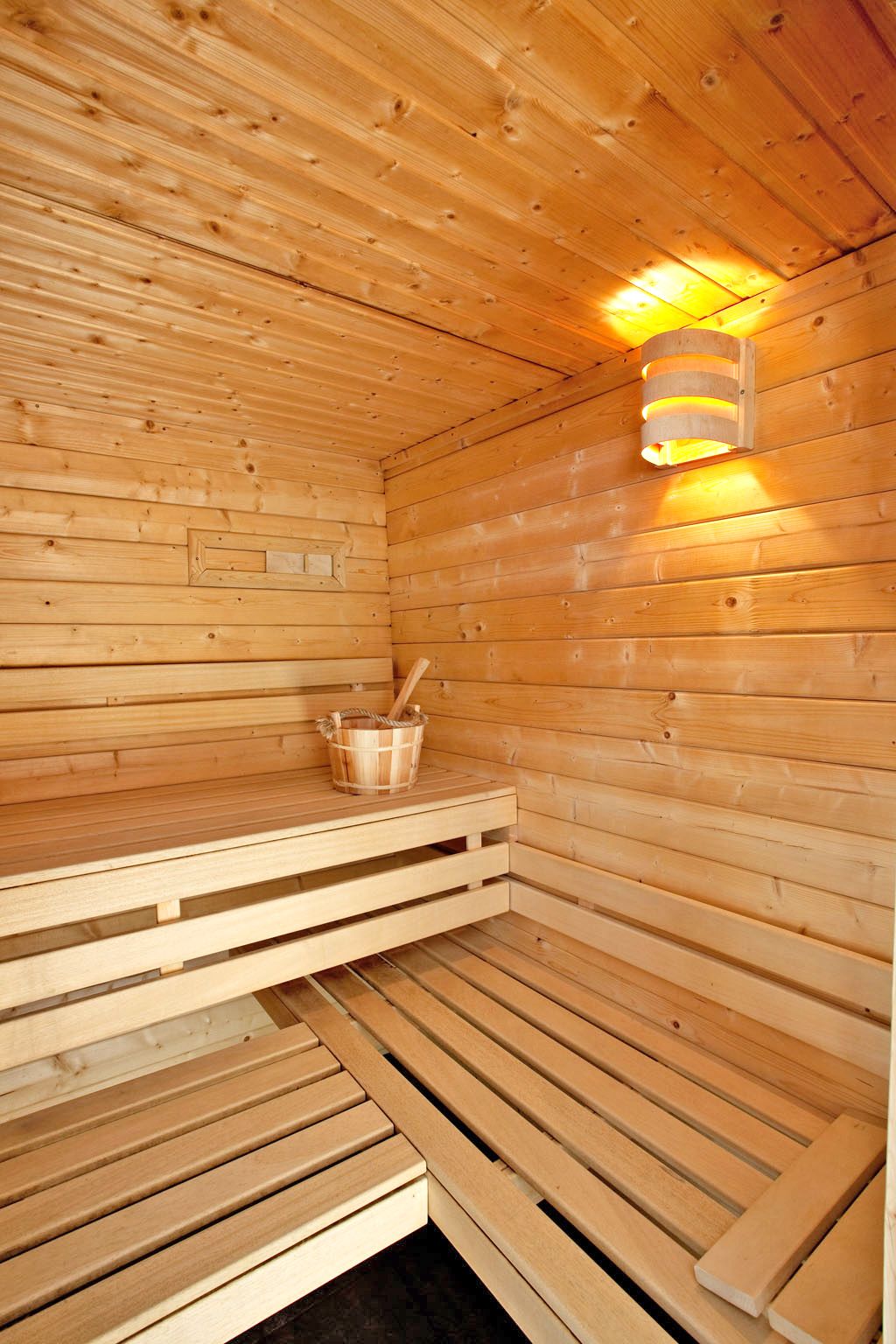 A wooden sauna with benches and a bucket.