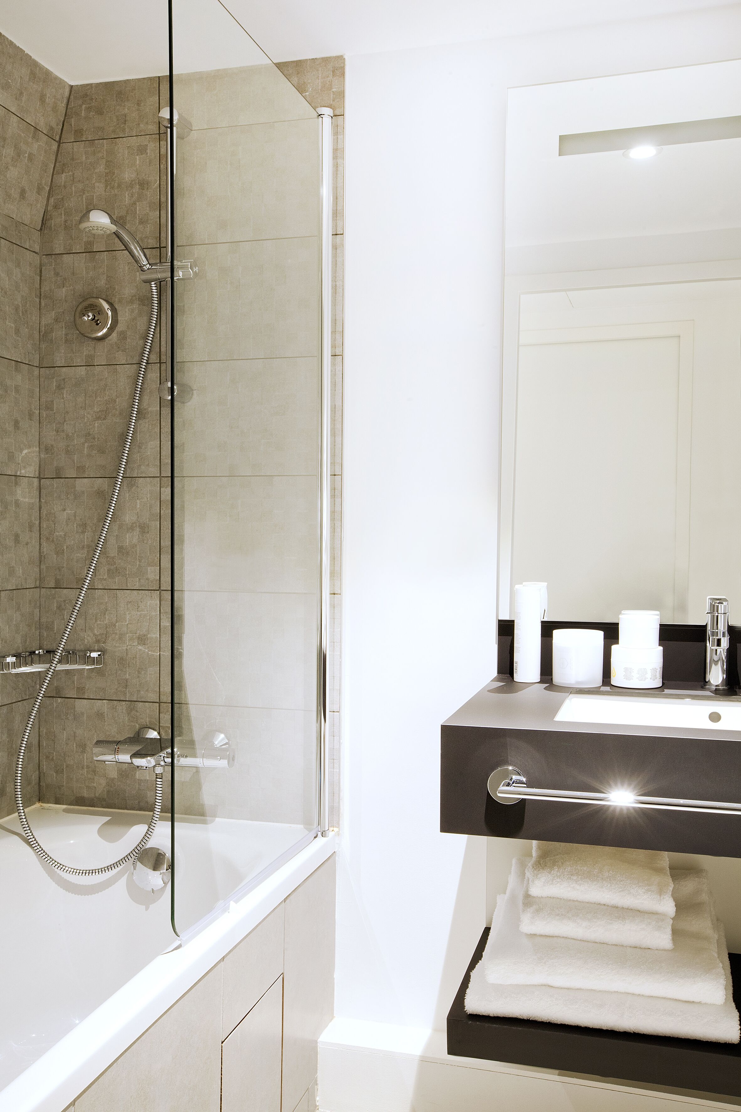 A modern bathroom with a glass-enclosed shower, a white sink, and neatly folded towels.