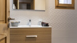 Une salle de bain avec un meuble-lavabo en bois, un miroir, un évier et une fenêtre.