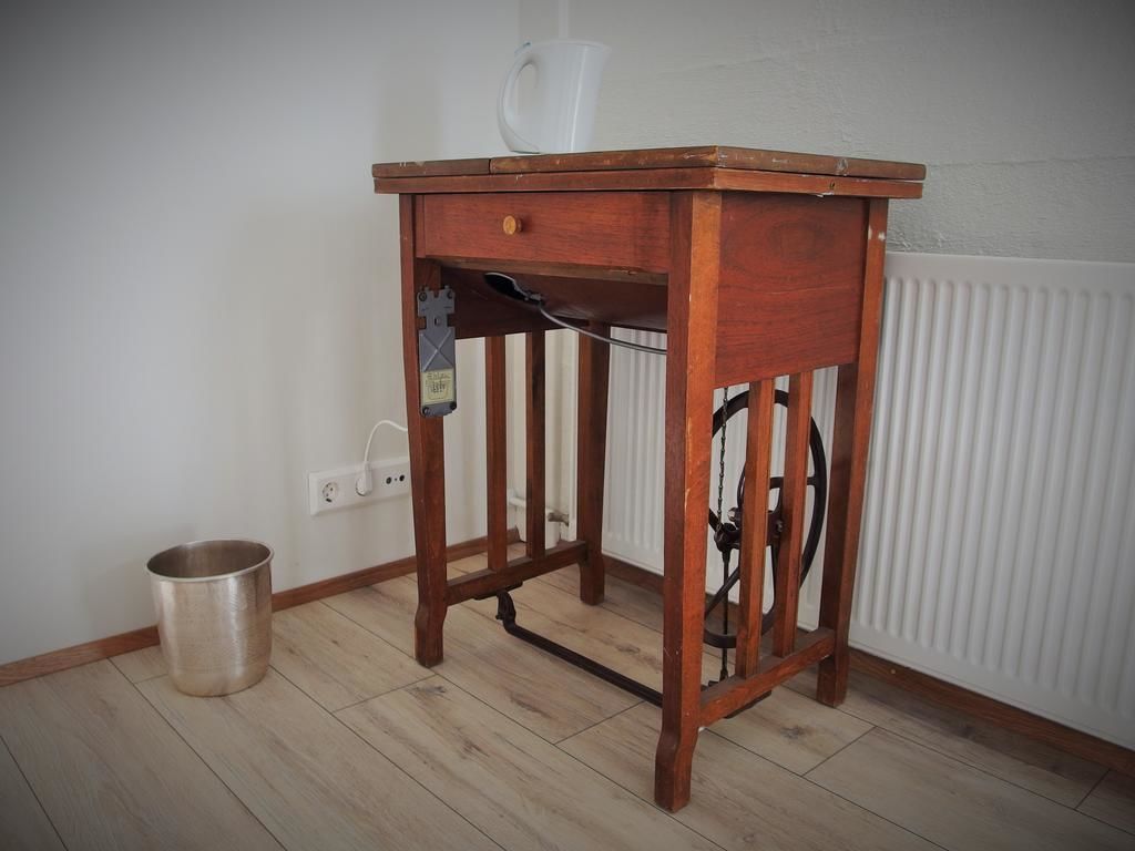 A wooden table with a drawer, a metal bucket, and a radiator in the background.