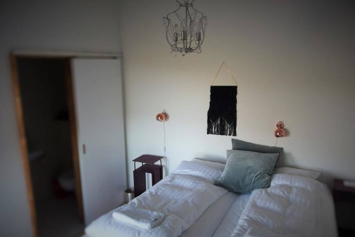 Ein Schlafzimmer mit zwei Betten, einer Pendelleuchte und einem kleinen Tisch mit Stuhl.