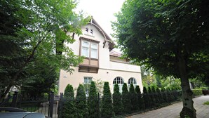 A two-story building with a beige facade, a balcony, and a black metal fence. - Grand Apartments - Loft (Sopot)