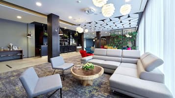 A modern lobby with a bar area, seating arrangements, and a large window providing natural light.