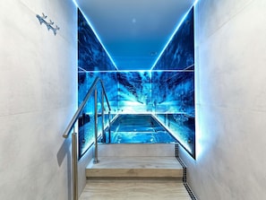 A modern staircase with a glass barrier, leading to a lower level.