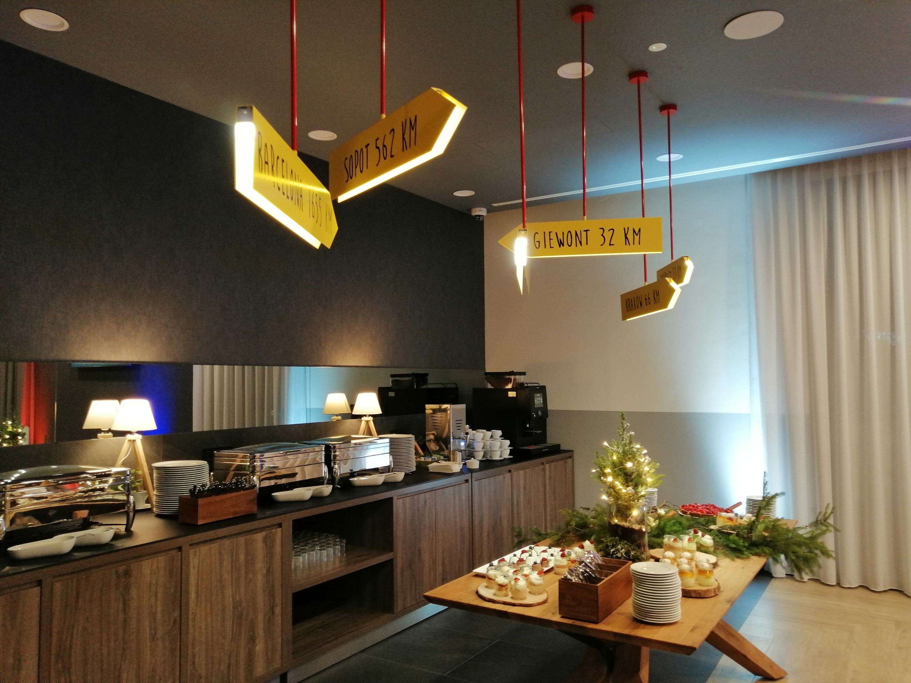 Zona de recepción de un hotel con un mostrador de madera, máquina de café y un pequeño árbol de Navidad.