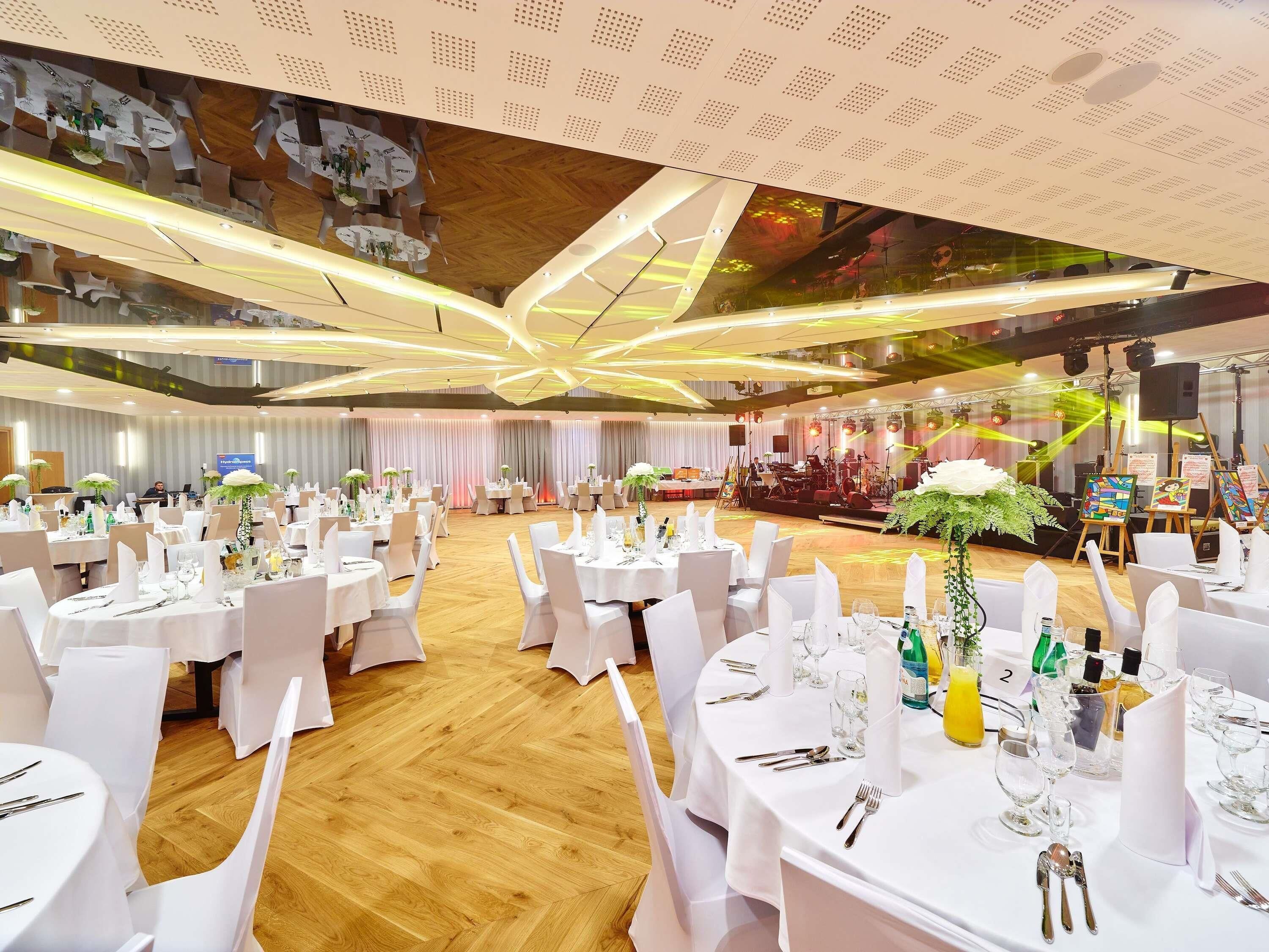 A banquet hall with round tables, white tablecloths, and chairs.
