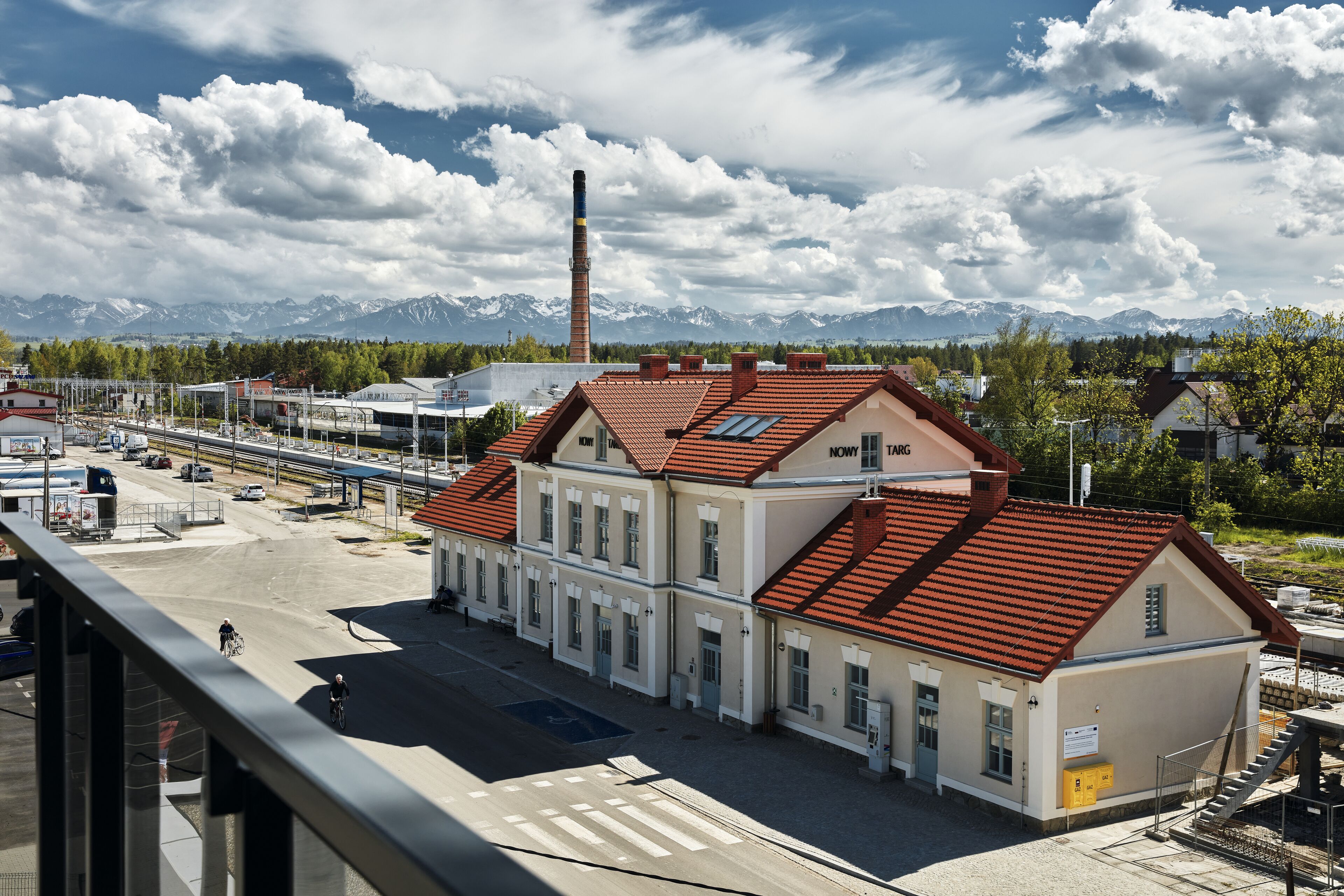 A building with a red-tiled roof, a large chimney, and a view of snow-capped mountains in the background.