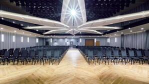 A conference room with rows of chairs, a wooden floor, and a modern ceiling design. - ibis Styles Nowy Targ (Nowy Targ)