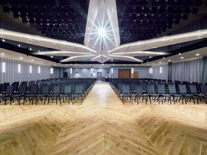 A conference room with rows of chairs, a wooden floor, and a modern ceiling design. - ibis Styles Nowy Targ (Nowy Targ)