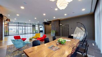 A modern conference room with a wooden table, red and blue chairs, and a hanging chair.