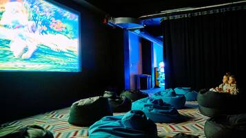 A cinema room with a large screen, bean bags, and a patterned carpet.