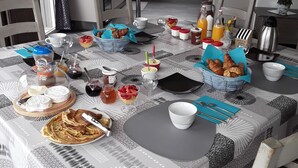 A dining area with a table set for breakfast, including pastries, fruit, and beverages. - Chambres d'hôtes de l'Orval (Thiergeville)
