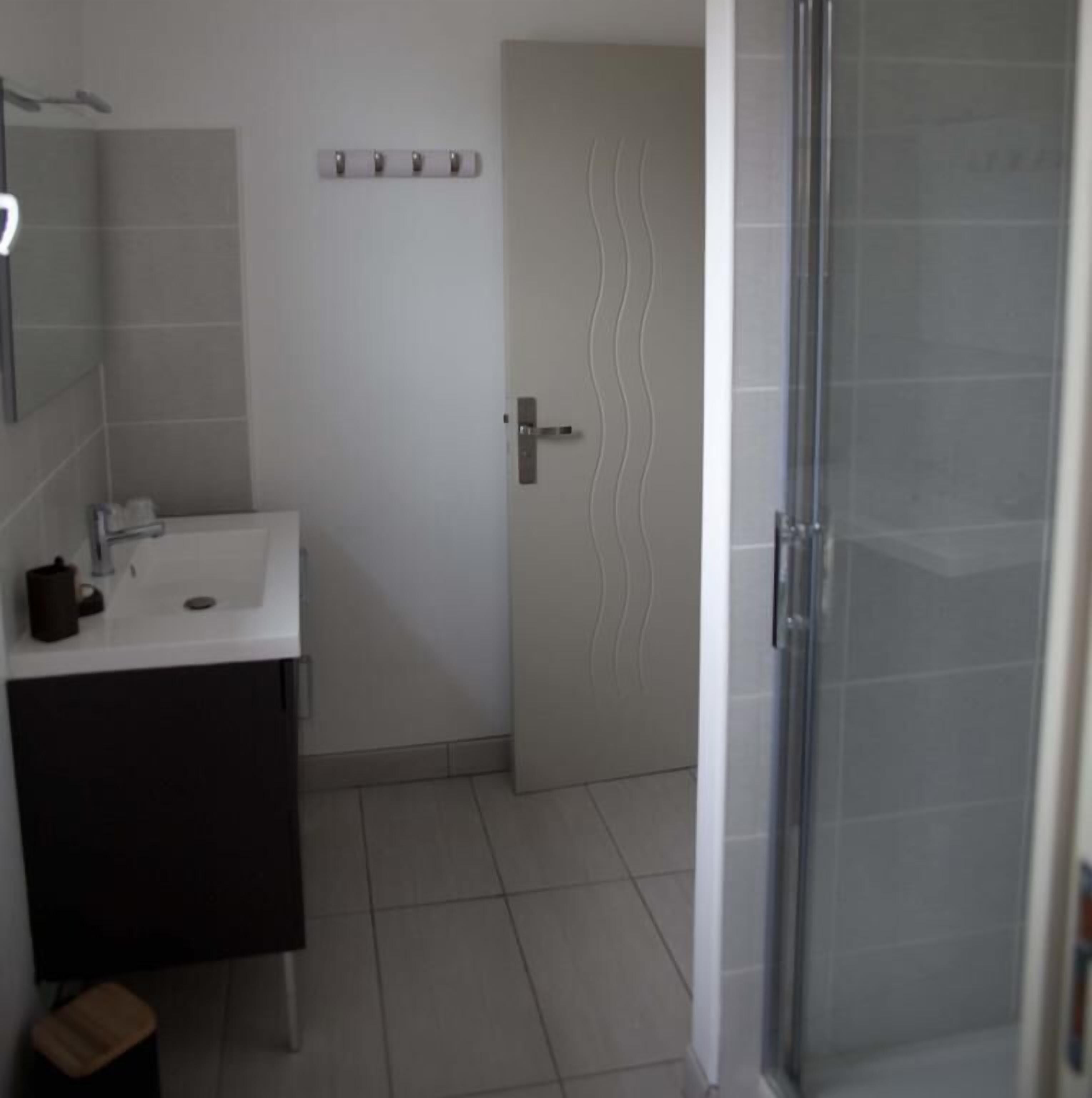 A bathroom with a white sink, a mirror, a towel rack, and a shower area.