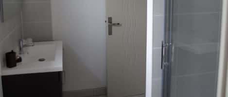 A bathroom with a white sink, a mirror, a towel rack, and a shower area.
