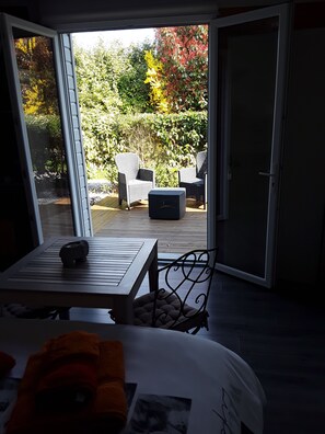 Habitación con puerta de vidrio corredera que da a un patio exterior con mobiliario de mimbre y vistas a un jardín.
