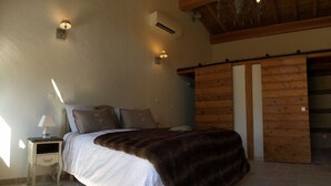 Une chambre à coucher comprenant un lit, une table de chevet, des lampes fixées au mur et une porte coulissante en bois.