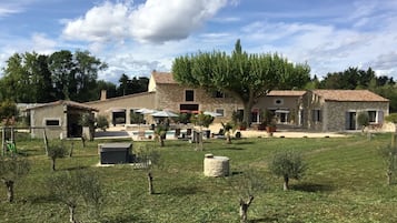 A rustic villa with a swimming pool, outdoor seating, and a well-maintained garden.