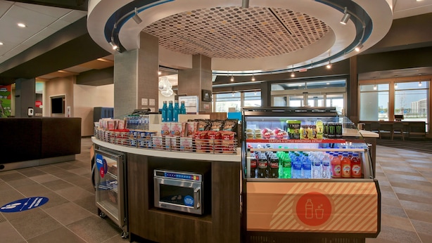 A self-service beverage station with a refrigerated display and a microwave. - Tru by Hilton Grand Prairie (Grand Prairie)