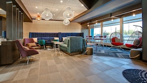 A modern lobby with a seating area, a reception desk, and large windows offering a view of the outdoors. - Tru by Hilton Grand Prairie (Grand Prairie)