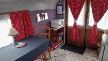 A compact room with a table, a chair, a microwave, and a small shelf.