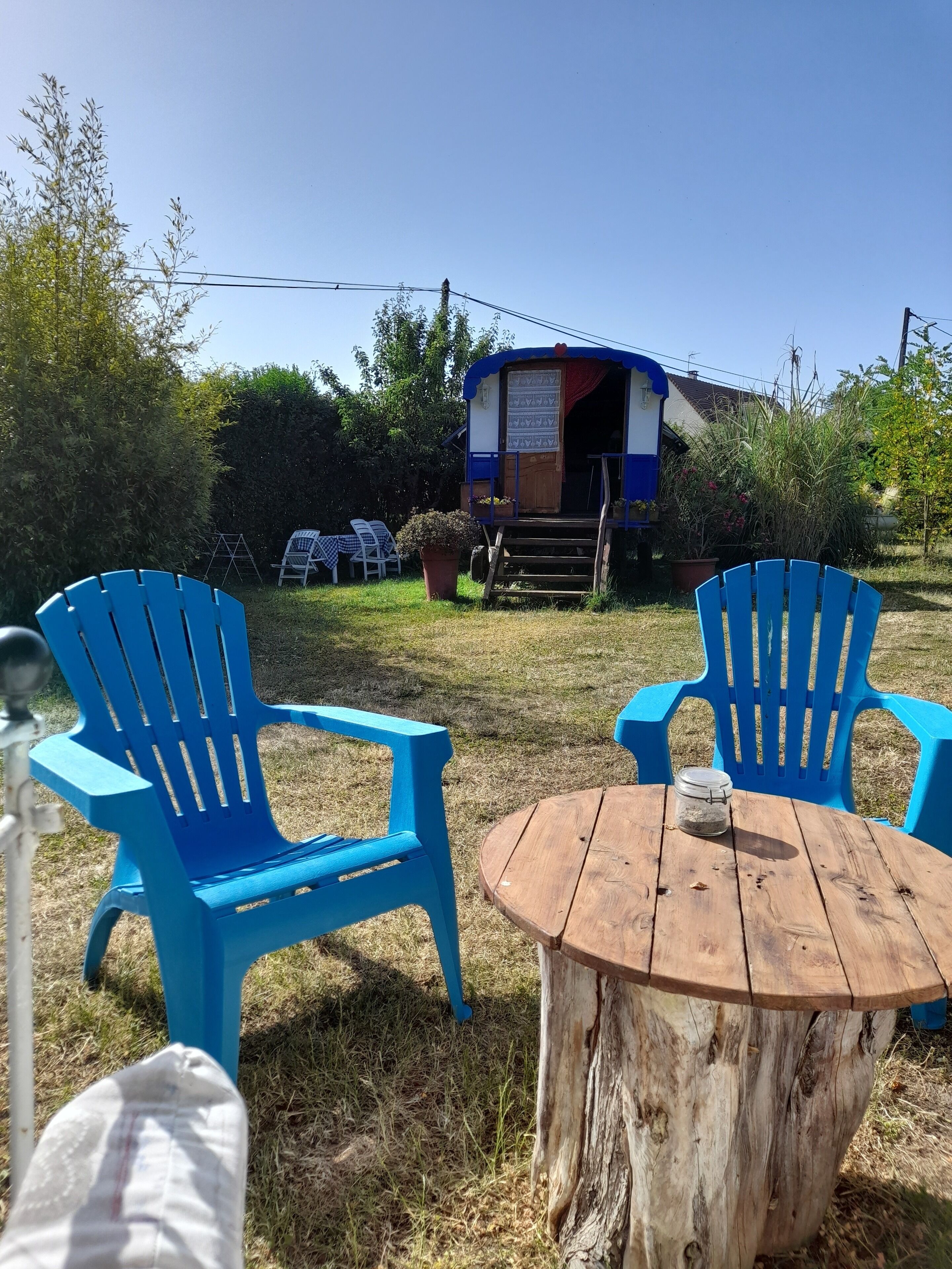 Een houten tafel met twee blauwe stoelen in een tuin.