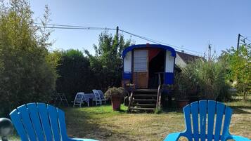 Een houten tafel met twee blauwe stoelen in een tuin.