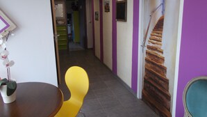 A hallway with purple walls, a staircase, and a dining area with a yellow chair. - Le Clos des Epinettes (Angé)