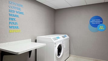 Una sala de lavandería con lavadora, tendedero y una pared con instrucciones para el lavado.