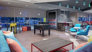 Un área de estar moderna con mesa de fútbol, asientos cómodos y una zona de bar.