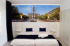Habitación de hotel con una cama grande, dos mesitas de noche y vista a un edificio histórico con una torre del reloj.