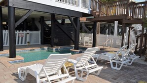 Un área de piscina con sillas reclinables blancas y una valla de piquetes blancos.