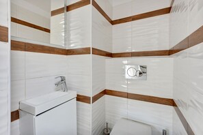 A bathroom with white tiles and wooden accents, a white sink, and a mirror with a silver frame. - Grand Apartments - Love Loft (Sopot)
