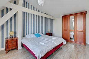 A bedroom with a bed, a nightstand, a wooden wardrobe, and a striped wall. - Grand Apartments - Love Loft (Sopot)