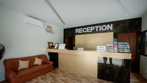 A reception area with a reception desk, a brown sofa, and a sign for tours and booking. - Coconut  Grove Hotel Samui - Hostel (Koh Samui)