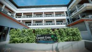 A multi-story hotel with a sign for Coconut Grove Hotel. - Coconut  Grove Hotel Samui - Hostel (Koh Samui)