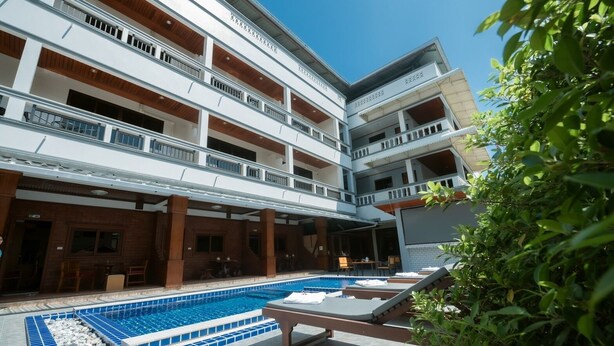 A multi-story hotel with a swimming pool, outdoor seating, and a covered patio area. - Coconut  Grove Hotel Samui - Hostel (Koh Samui)