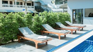A poolside area with lounge chairs and a swimming pool. - Coconut  Grove Hotel Samui - Hostel (Koh Samui)