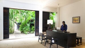 A reception desk with a person seated behind it, a lamp, and a framed picture on the wall. - Mittali Hotel (Sihanoukville)