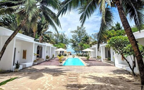 Una piscina al aire libre, sombrillas, tumbonas