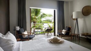 A hotel room with a bed, two chairs, a floor lamp, and a view of a balcony with plants. - Mittali Hotel (Sihanoukville)