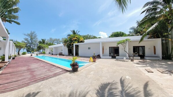Relax by the serene pool surrounded by palm trees and tropical plants.