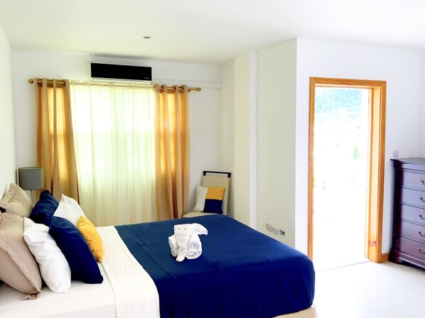 A hotel room with a bed, a nightstand, a lamp, a dresser, and a window with curtains.