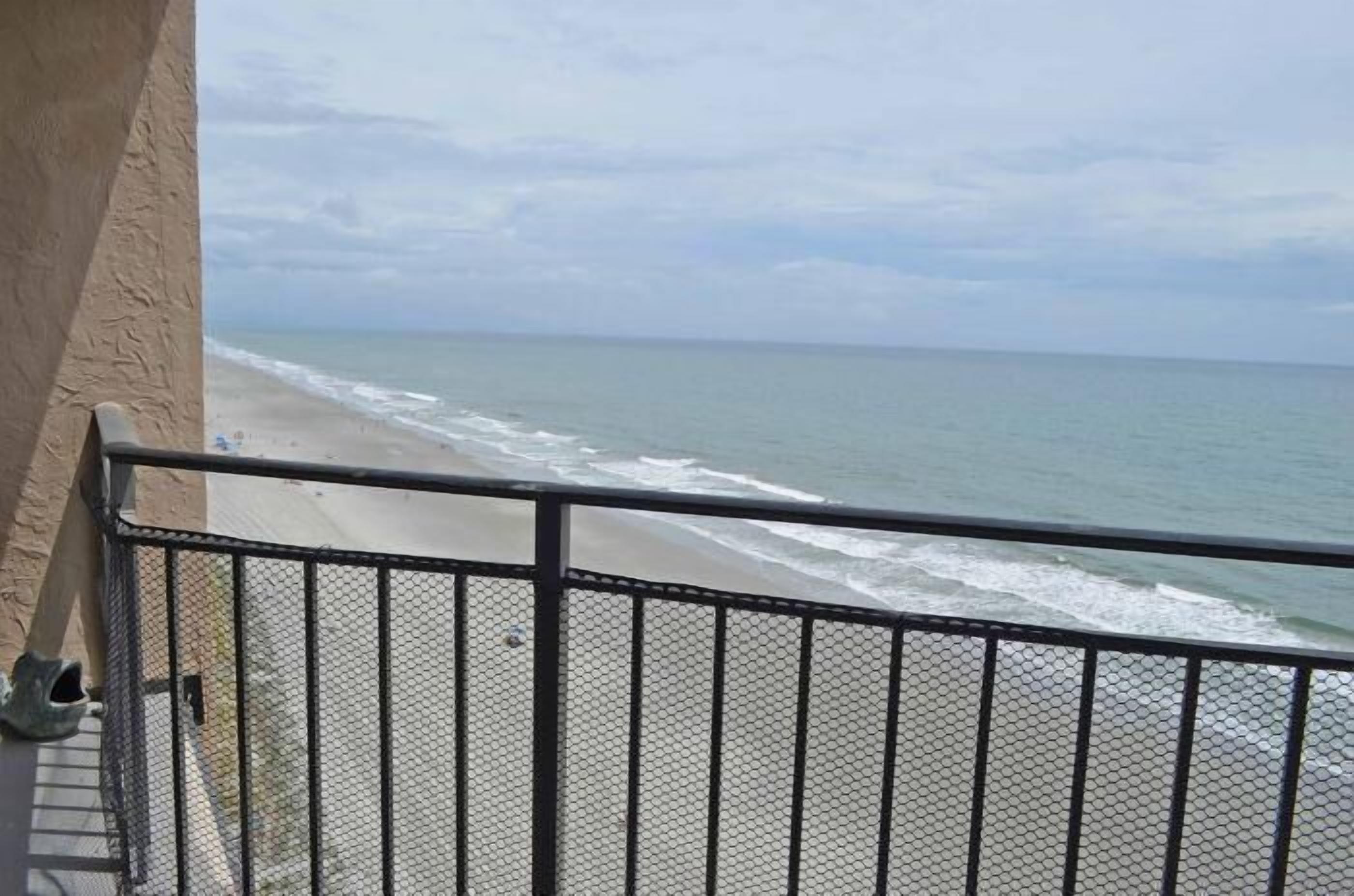 A balcony with a view of a beach and ocean.