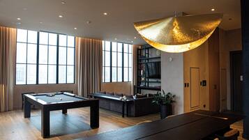 A modern room with a pool table, a sofa, and a dining table.
