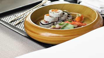 A tray with sushi, a martini glass, and a white pitcher.