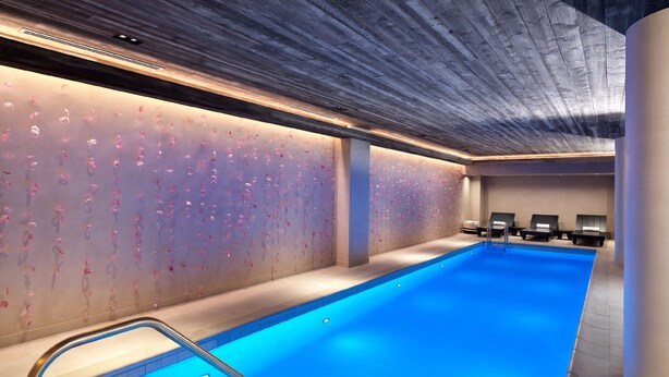 A modern indoor swimming pool with a clear blue water surface, a wooden ceiling, and a wall with a floral pattern. - Nobu Hotel Chicago (Chicago)