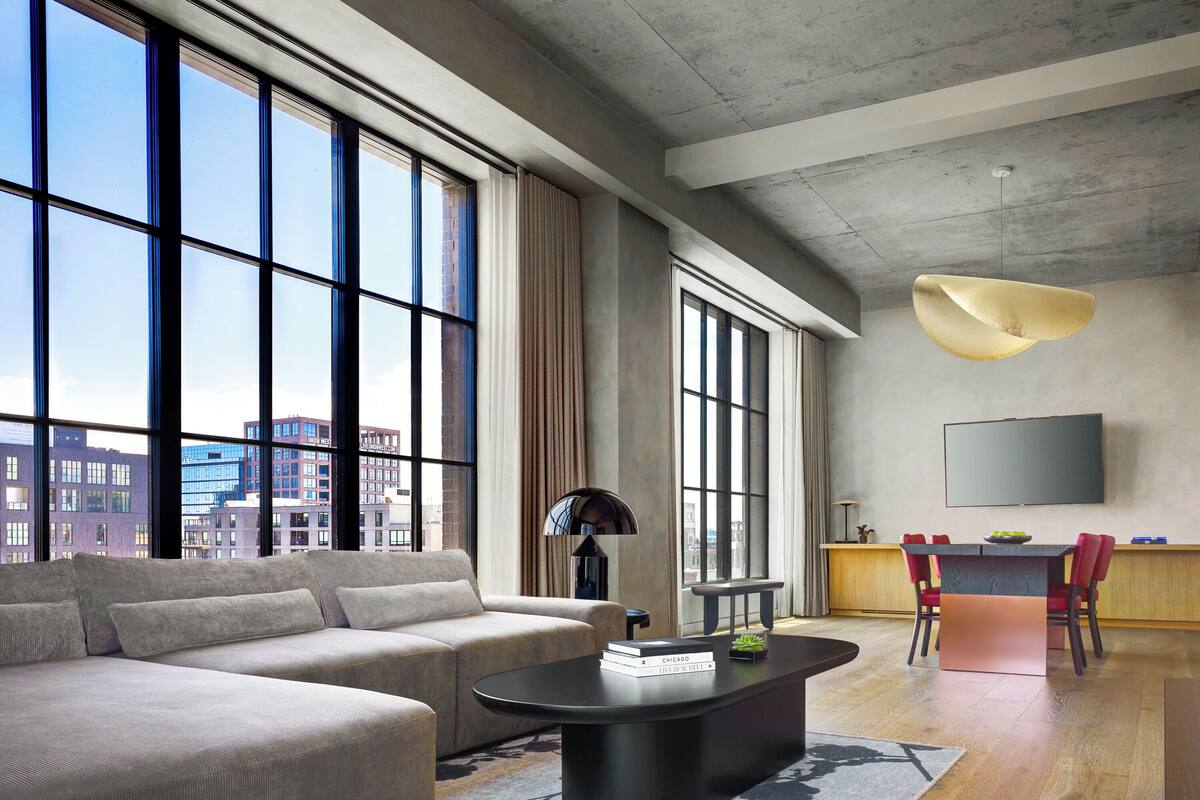 A modern living room with a large window, a sofa, a coffee table, a TV, and a dining area.