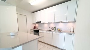A modern kitchen with white cabinets, a built-in oven, and a stainless steel sink.